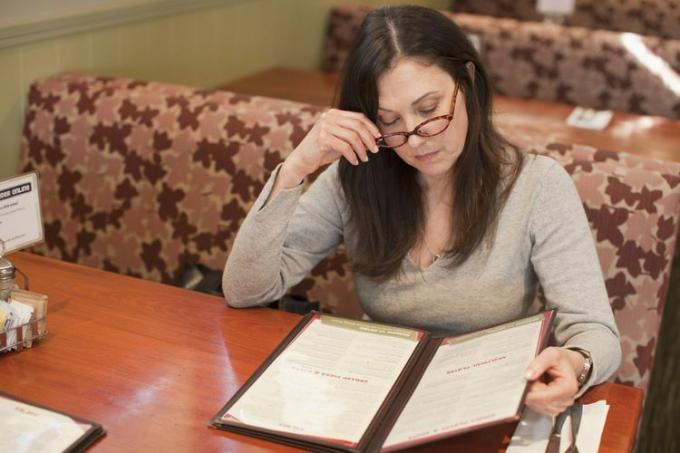 Kaukasische vrouw die menu in restaurant bekijkt