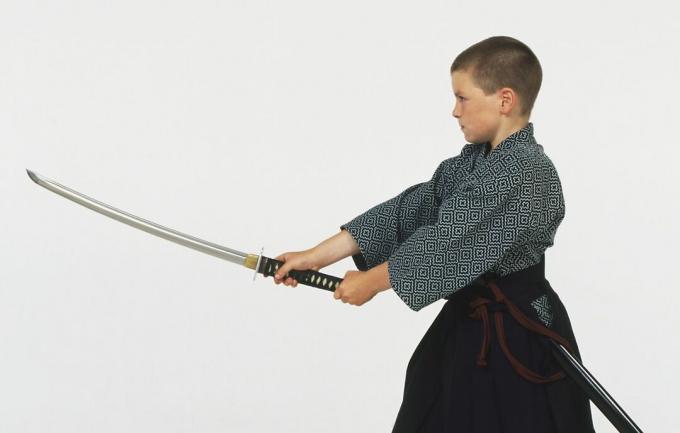 Zēns tur ar abām rokām izvilktu Iaido zobenu.