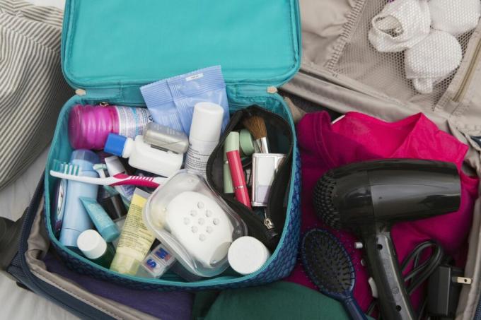 Una maleta con un neceser abierto y un secador de pelo.
