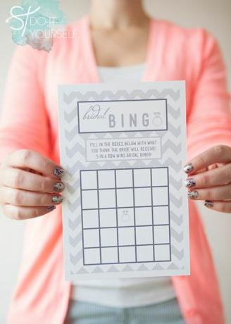 Una mujer sosteniendo una tarjeta de bingo de despedida de soltera