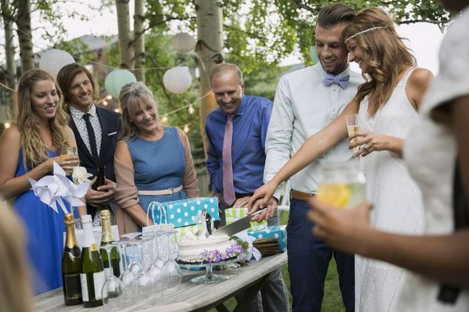 Bruden och brudgummen skär tårta på bröllopsmottagning