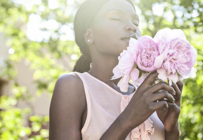 屋外で花の香りを呼吸する女性