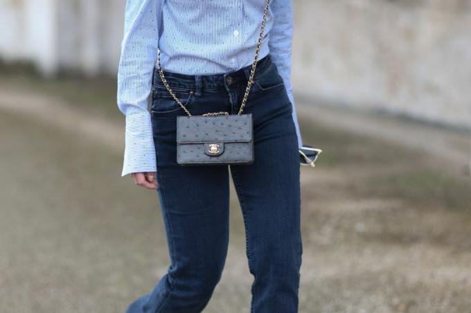 Ženska oblečena v temno modre kavbojke in torbico Chanel