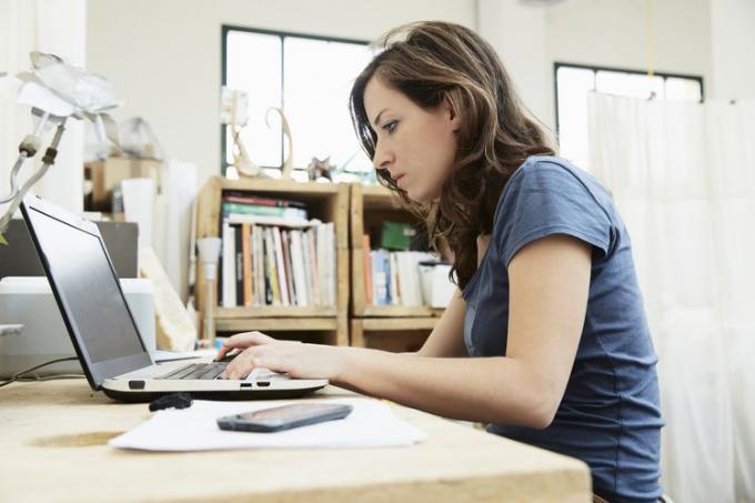 mujer joven, sentado, en el escritorio, usar la computadora portátil