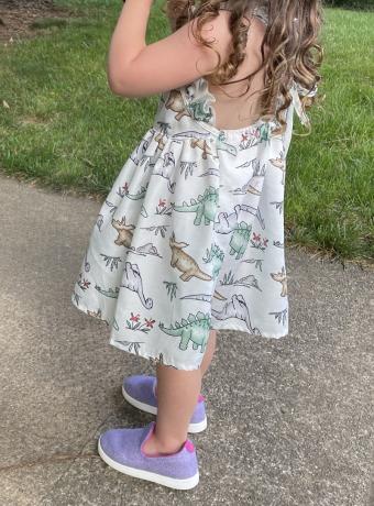 En liten jente står på et fortau iført lilla Allbirds ullstoler.