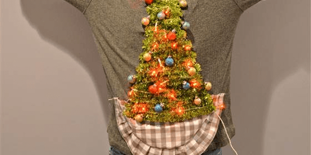 Seorang pria mengenakan sweter Natal jelek dengan pohon di atasnya