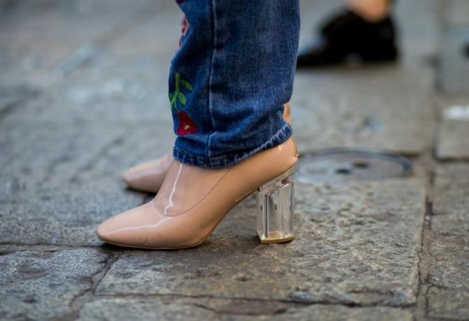 Pies de mujer en zapatos nude con tacones de plástico transparente