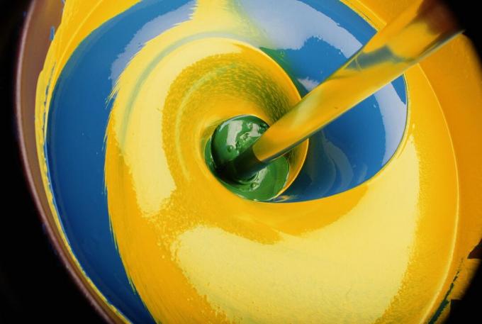 Remolino de pintura amarilla y azul produciendo verde, close-up