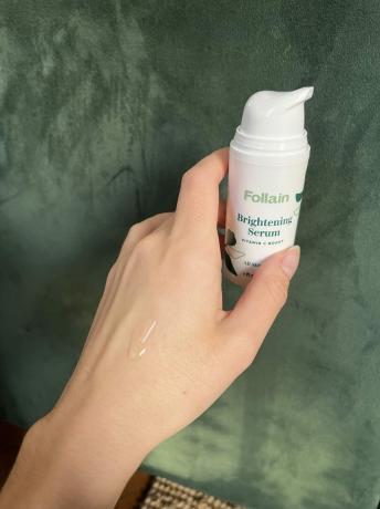 Roka, ki drži posvetlitveni serum Follain