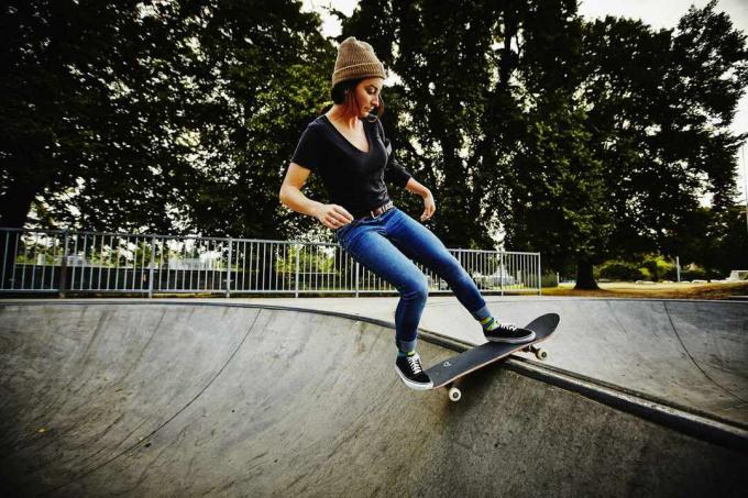 Kobieta deskorolkarz balansuje na grzbiecie miski w skate parku