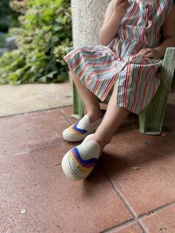 एक छोटी लड़की रोथिस पहने हुए एक छोटी कुर्सी पर आराम कर रही है।