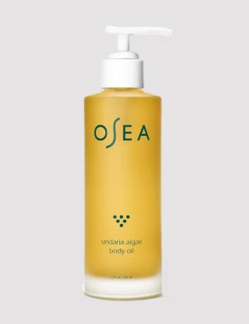 Пляшка олії для тіла OSEA в сірому студійному знімку.