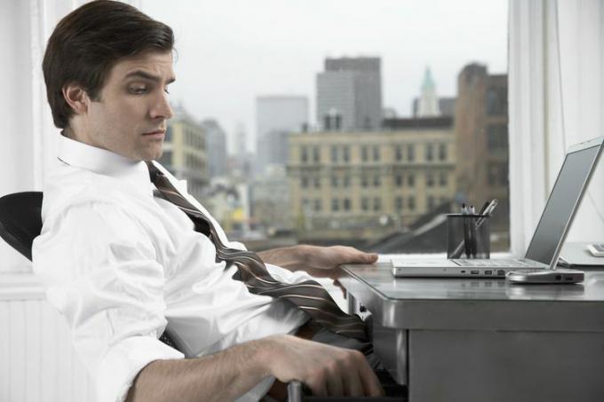Homme avec un tiroir de bureau d'ouverture d'ordinateur portable