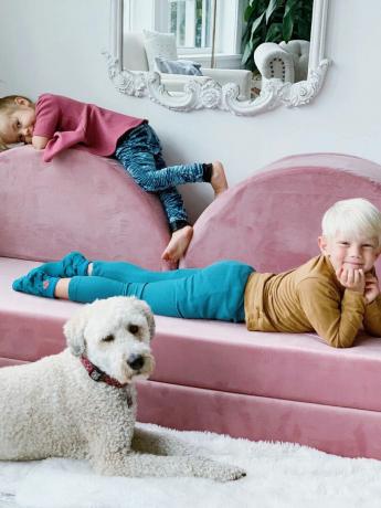 İki çocuk ve bir köpek, pembe oyun kanepelerinin etrafında uzanıyor.