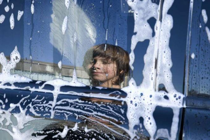 Gutters refleksjon i et vindu på en bil