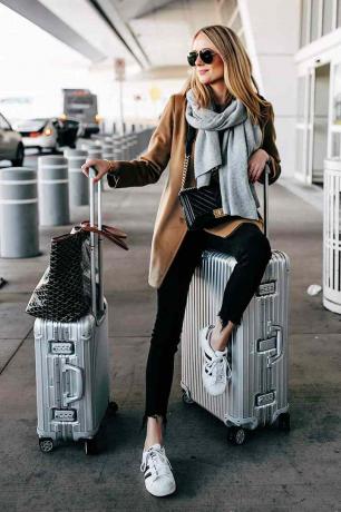 Nő elegáns repülőtéri ruhában, csomagokkal