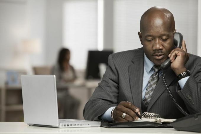 Hombre de negocios negro usando teléfono en el escritorio