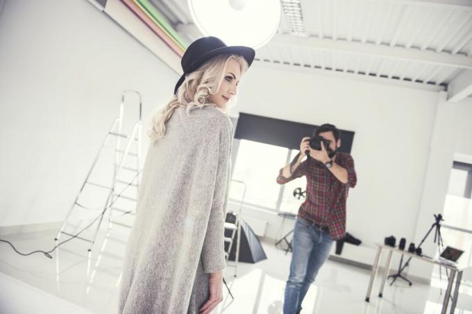 Mužský fotograf fotografující modelku na studiovém bílém pozadí