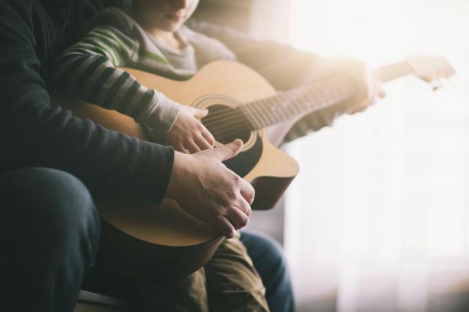 pappa lär sin son spela gitarr