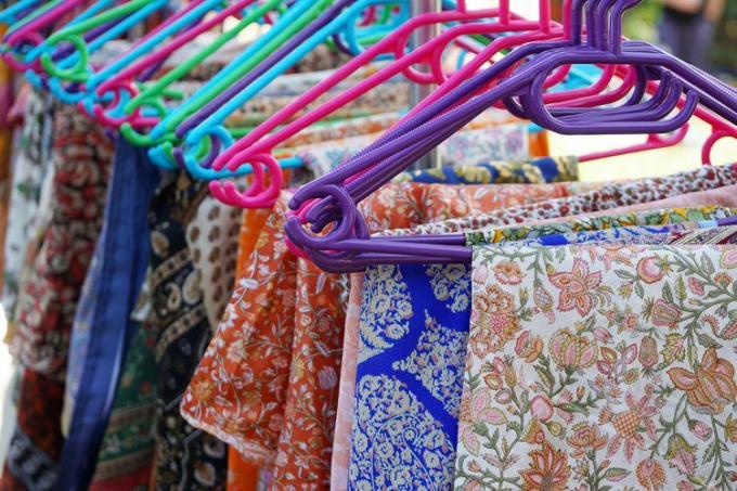 Close-up van kleding met kleurrijke patronen die aan kleerhangers hangt op de markt