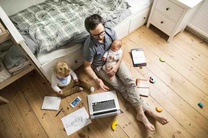 Pai com seu filho pequeno e filha bebê trabalhando em casa