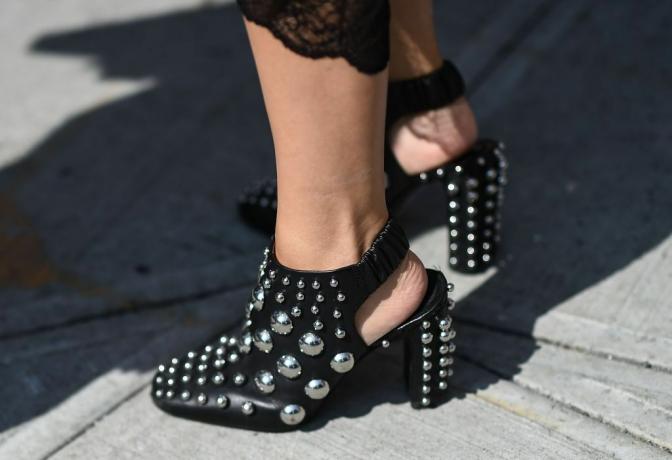 Pies de mujer en zapatos negros con cristales y perlas