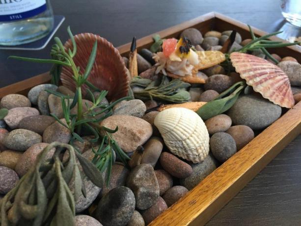maistas patiekiamas dėžėje su akmenimis ir kriauklėmis