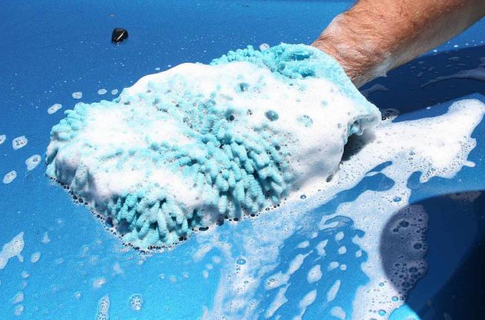 Close-up de guante de lavado en coche con espuma.