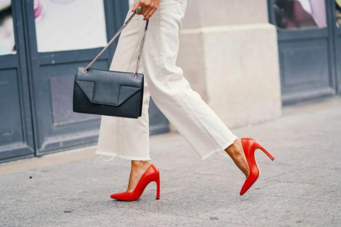 Ženské nohy v bílých kalhotách a oranžových botách na vysokém podpatku