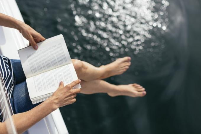 Жена седи на ветроходна лодка и чете книга