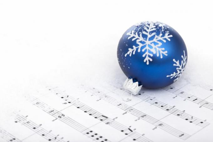 Een blauwe kerstversiering bovenop bladmuziek.