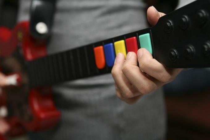 Человек, держащий контроллер Guitar Hero