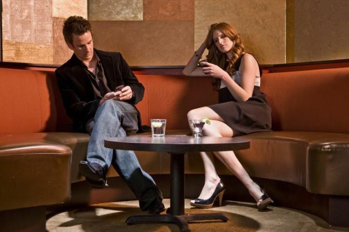 Deux employés concentrés sur leur téléphone, assis à côté d'un événement au bureau.