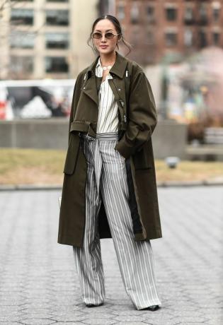 אישה בסגנון רחוב בתלבושת סתיו עם מכנסיים ומעיל טרנץ'