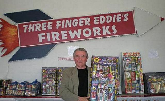 En mann viser fyrverkeri nær et skilt for " Three Finger Eddie's"