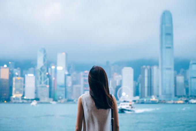 Widok z tyłu podróżniczki cieszy się widokiem na Victoria Harbour i panoramę Hongkongu o zmierzchu