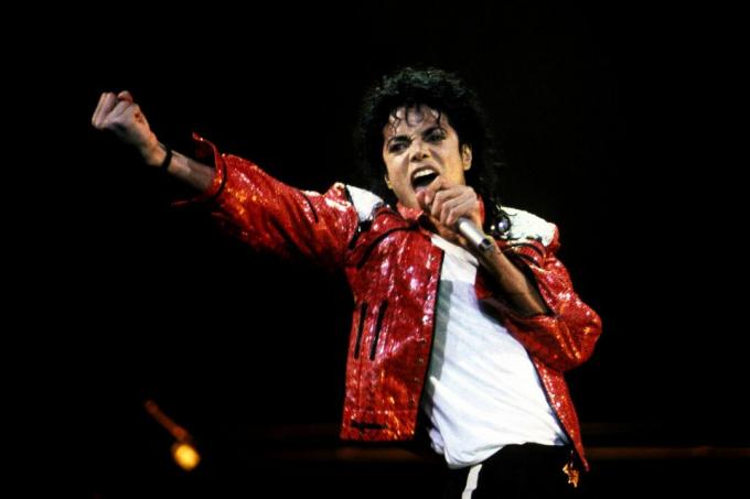 Michael Jackson, ışıltılı kırmızı deri ceketiyle sahnede dinamik bir varlık.