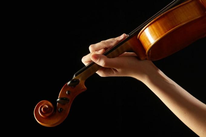 Mão feminina no violino da escala