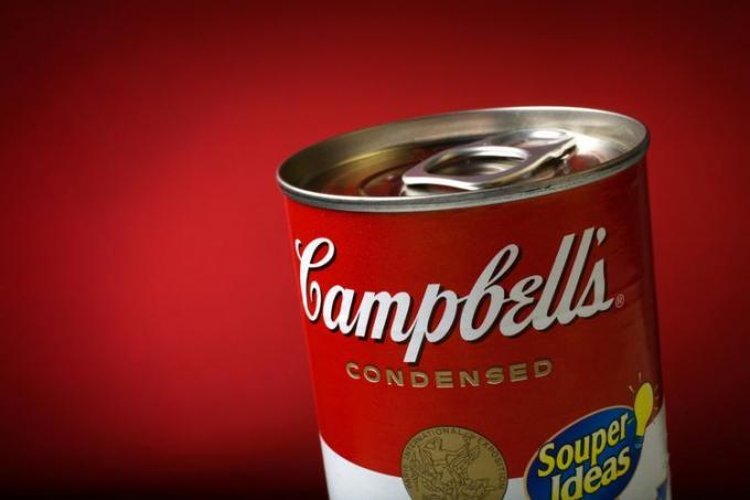 Primer plano de una lata de sopa Campbell's sellada sobre fondo rojo.