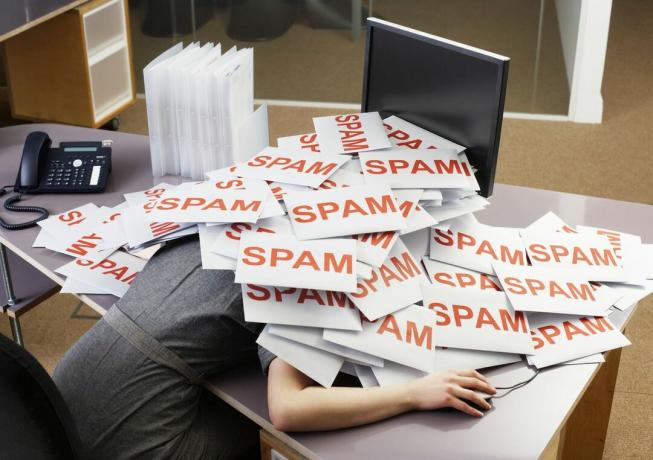 Giovane imprenditrice alla scrivania dell'ufficio con una pila di buste di spam