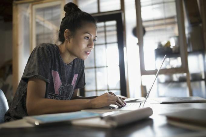 Ofiste dizüstü bilgisayarda çalışan odaklı genç kadın