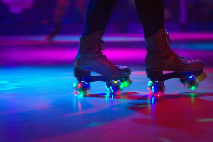 Nízka časť osoby na kolieskových korčuliach na podlahe na osvetlenom klzisku