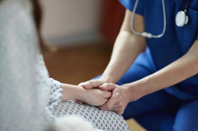 Περικομμένη εικόνα νοσοκόμας που κρατά το χέρι του ασθενούς
