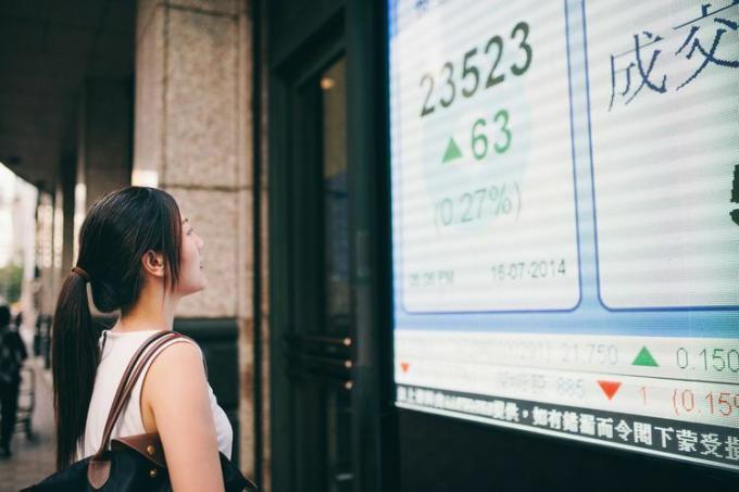 Una mujer de negocios mirando un tablero de cotizaciones de acciones.