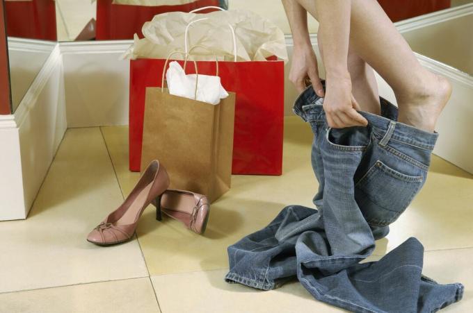 Wanita mencoba jeans di ruang ganti toko
