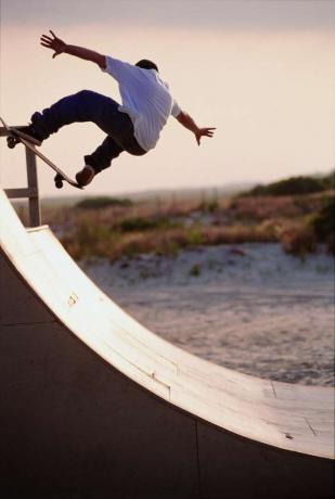Teenage boy skate sur rampe, vue arrière.
