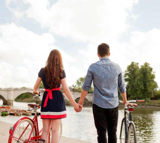 زوجان مع دراجات تبحث في منظر النهر.