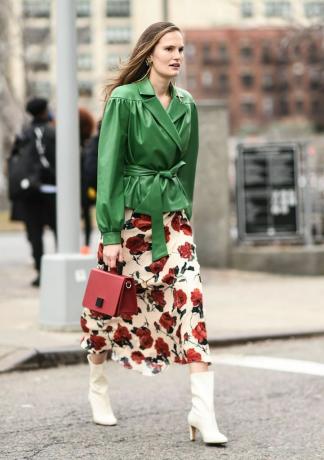 Ženska v uličnem slogu v zeleni usnjeni jakni in obleki s cvetličnim potiskom