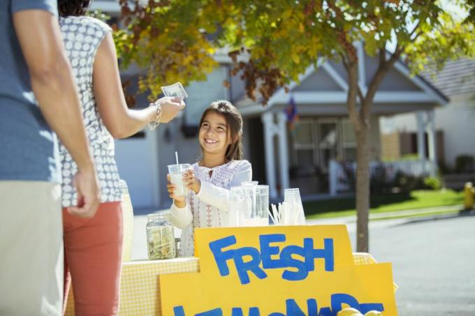Flicka som säljer lemonad på lemonad stativ