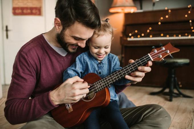 Anak perempuan dan ayah bermain gitar